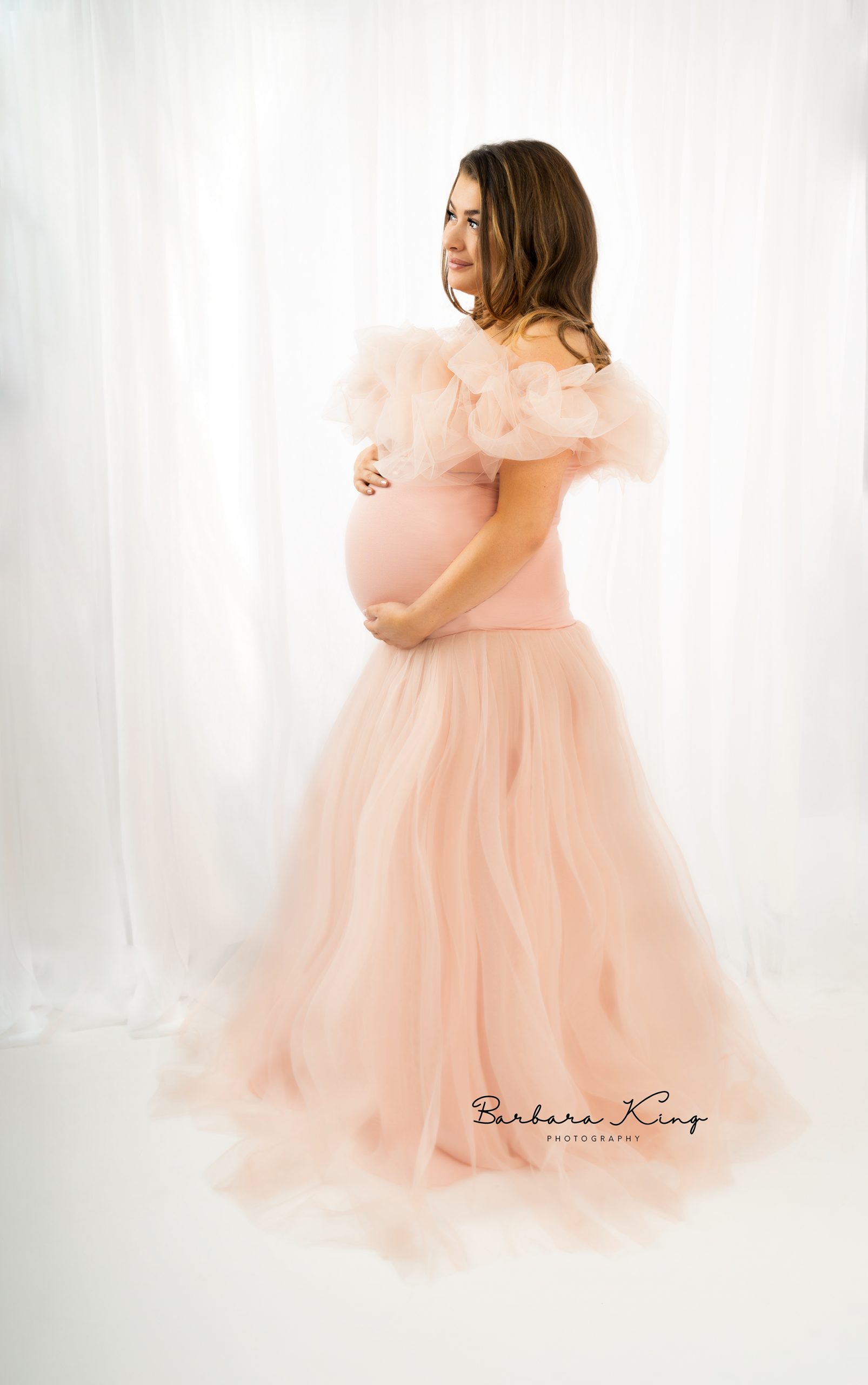 pregnant lady sitting on floor in pink dress with flowers in her hair